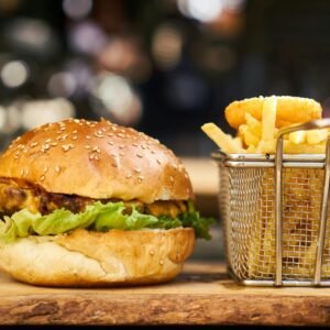 A delicious cheeseburger with crispy french fries served on a wooden platter, perfect for lunch or dinner.