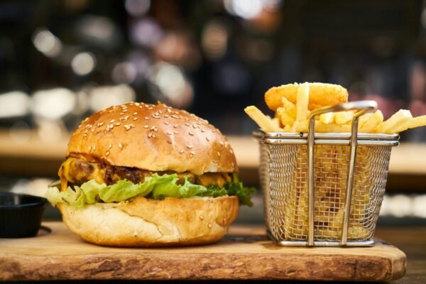 A delicious cheeseburger with crispy french fries served on a wooden platter, perfect for lunch or dinner.