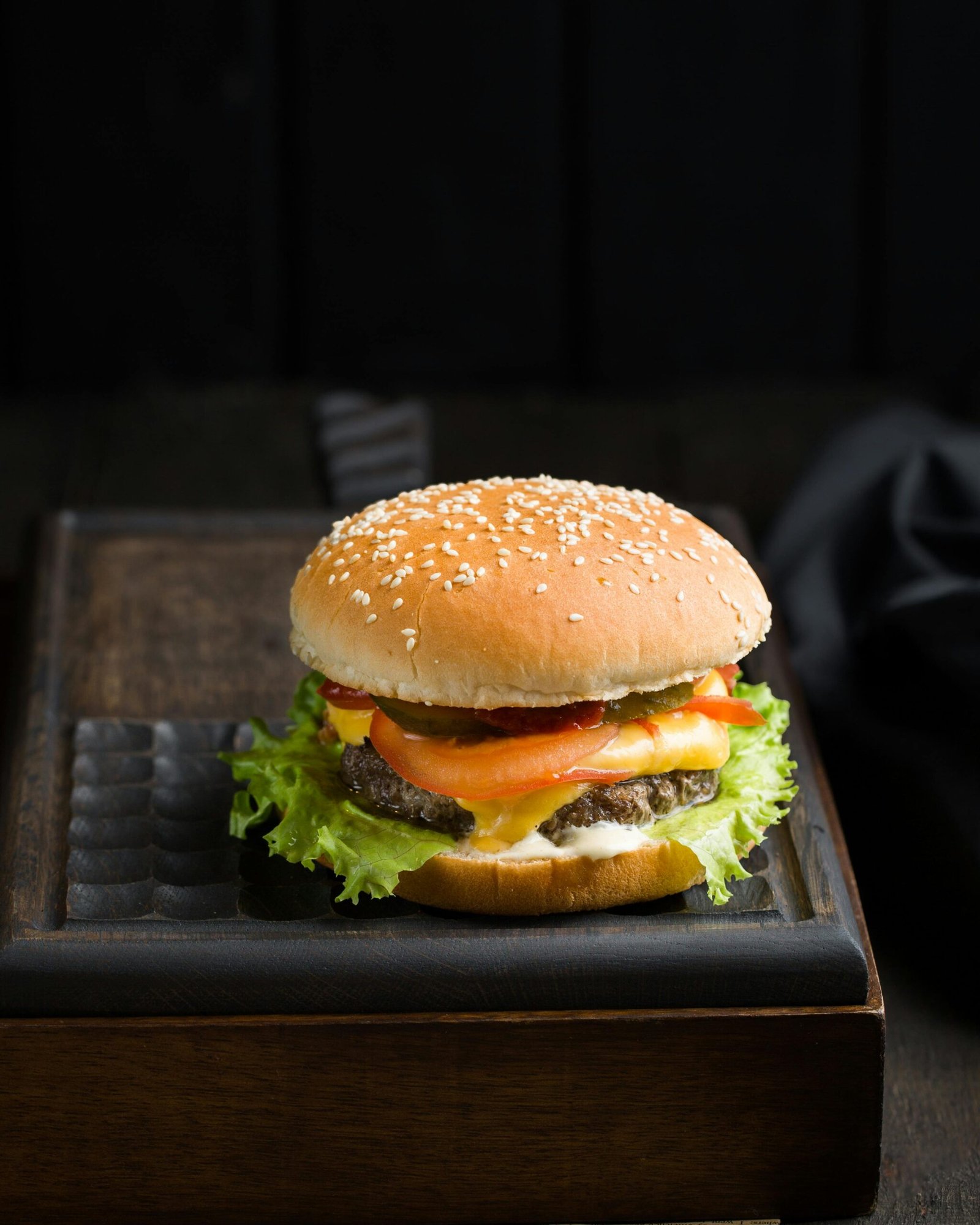 Close-up of a delicious cheeseburger with lettuce, tomato, and cheese on a sesame seed bun.