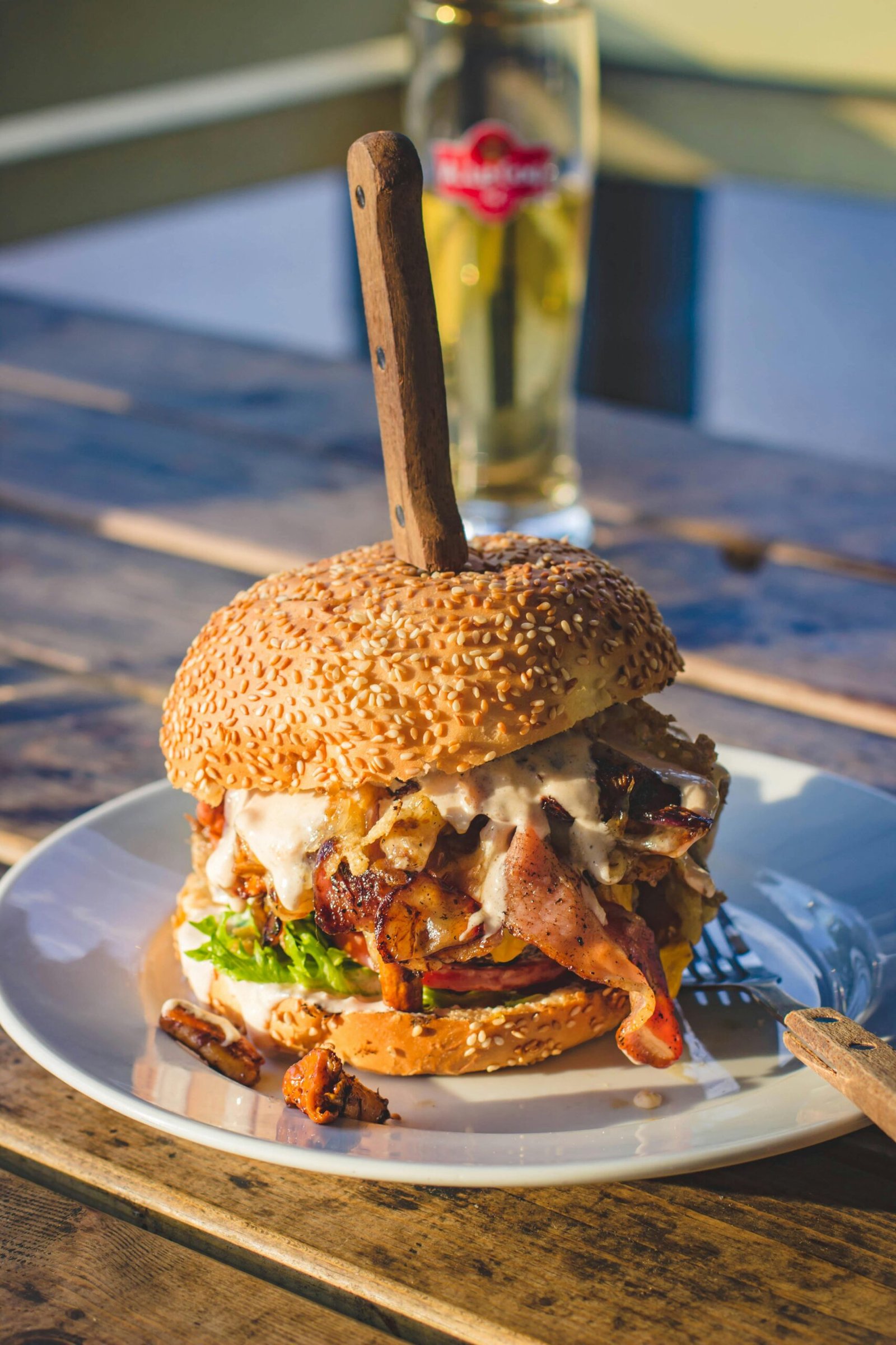 Delicious gourmet burger packed with bacon, cheese, and sauce on a sunny day.